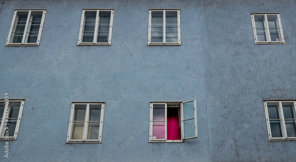 Eine trostlose Fassade in einem alten Mietshaus. Fenster mit rotem Vorhang Eine trostlose Fassade in einem alten Mietshaus. Fenster mit rotem Vorhang