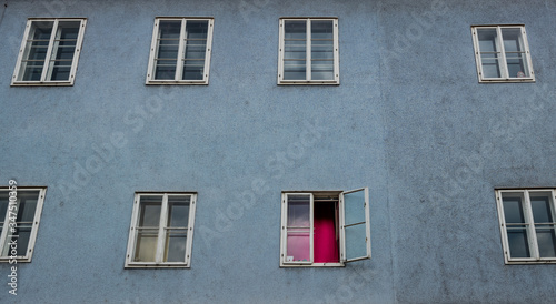 Eine trostlose Fassade in einem alten Mietshaus. Fenster mit rotem Vorhang