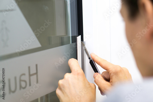 Signmaker cuts adhesive film on the window