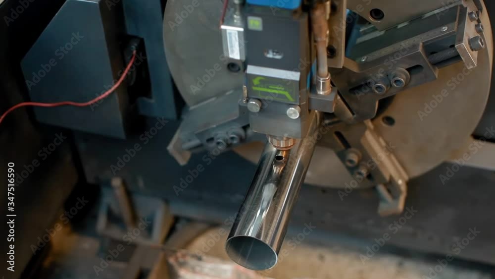 Laser cutting process, making a hole in metal tube. Modern industrial CNC machine smart equipment. Sparks at metalworks in workshop. Top of view Laser cutting process, making a hole in metal tube. Modern industrial CNC machine smart equipment. Sparks at metalworks in workshop. Top of view