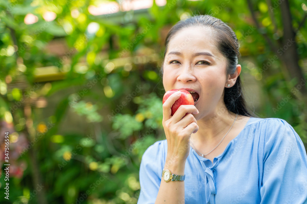 Beautiful cheerful asian woman eating fresh apple in green park Beautiful cheerful asian woman eating fresh apple in green park