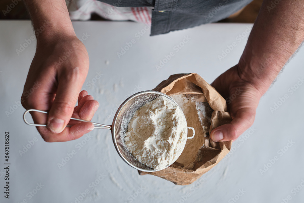 Man holds a bag of flour in his hands. Flour sieve. Preparing the dough for baking. Making homemade cuisine for family. Chef in the kitchen cooking pastry. Healthy delicious culinary recipe