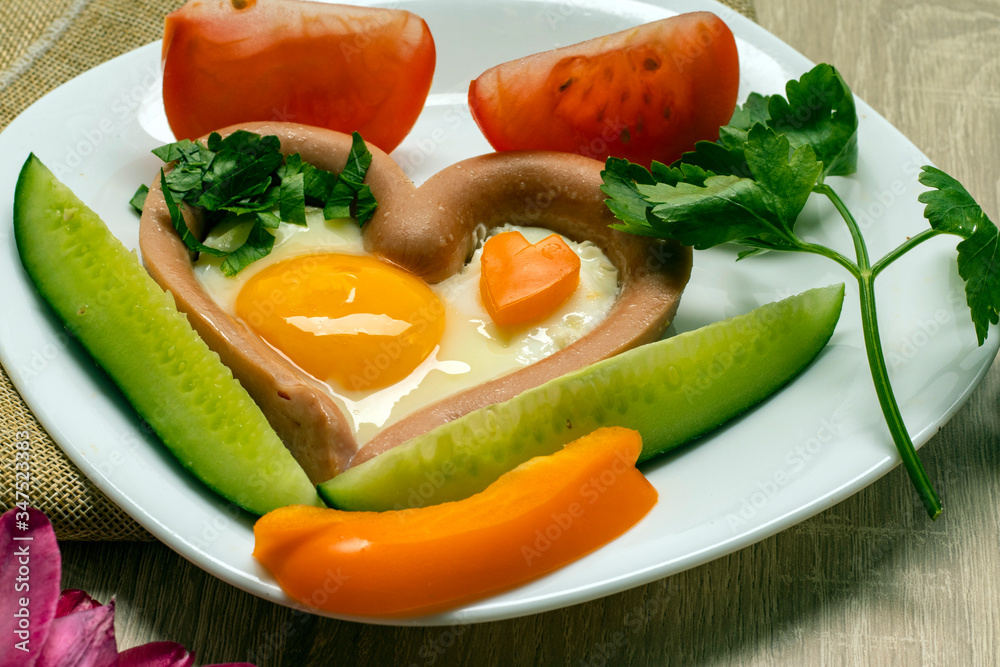 Creative breakfast. Fried eggs, sausages, toasts, tomatoes on a wooden table. Breakfast on Valentine's Day. Top view with copy space. Creative breakfast. Fried eggs, sausages, toasts, tomatoes on a wooden table. Breakfast on Valentine's Day. Top view with copy space.