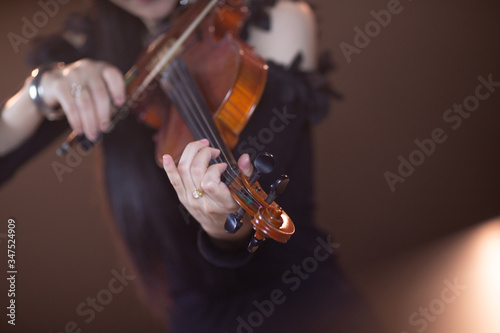 A pretty girl in a black dress playing the violin happily.