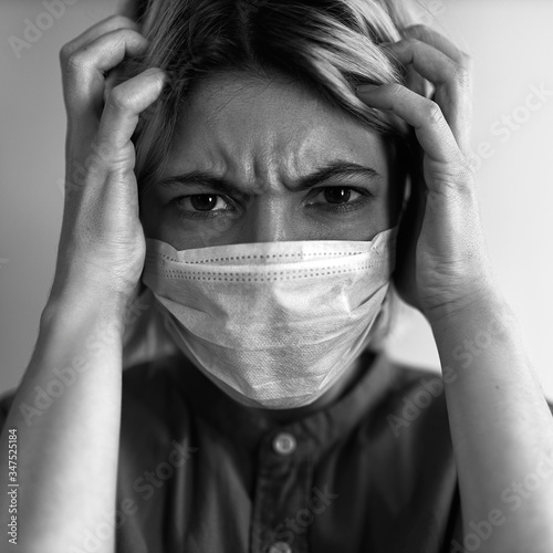 Fotografía Close up image of stressful worried young woman wearing sterile medical mask hol