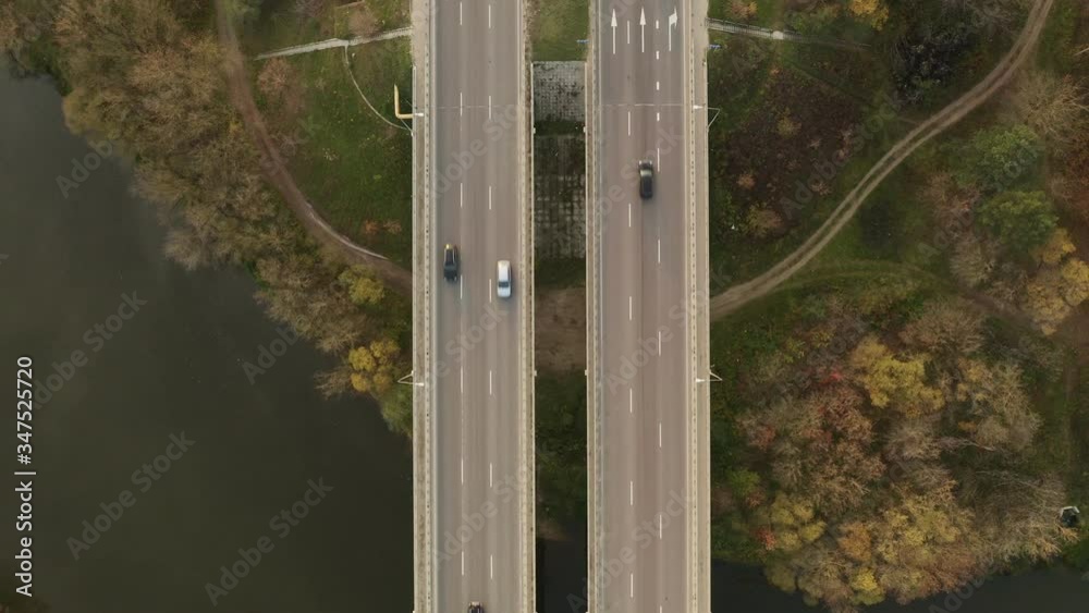 Aerial top-down view of the viaduct with the multilane highway over the river. Slow flying backward over a highway over the river. Sunny autumn day. Aerial top-down view of the viaduct with the multilane highway over the river. Slow flying backward over a highway over the river. Sunny autumn day.