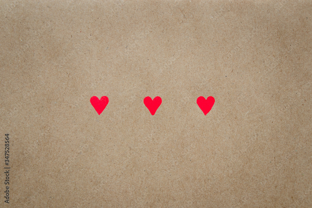 Fototapeta premium Image of three hearts on beige background of craft paper with copy space