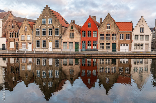 Buildings with reflections around channels in Bruges at sunset