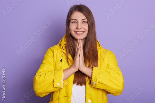 Closeup portrait of smiling female with palms together, standing and praying, lady looks hopeful, winsome woman poses smiling against lilac studio background. People emotions,body language concept. © sementsova321