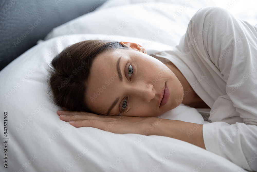 Close up face of melancholic 30s woman awakened lying in bed feels lonely, indifferent to new day, monotonous life, lack of energy and no motivation get up and do things, depression insomnia concept