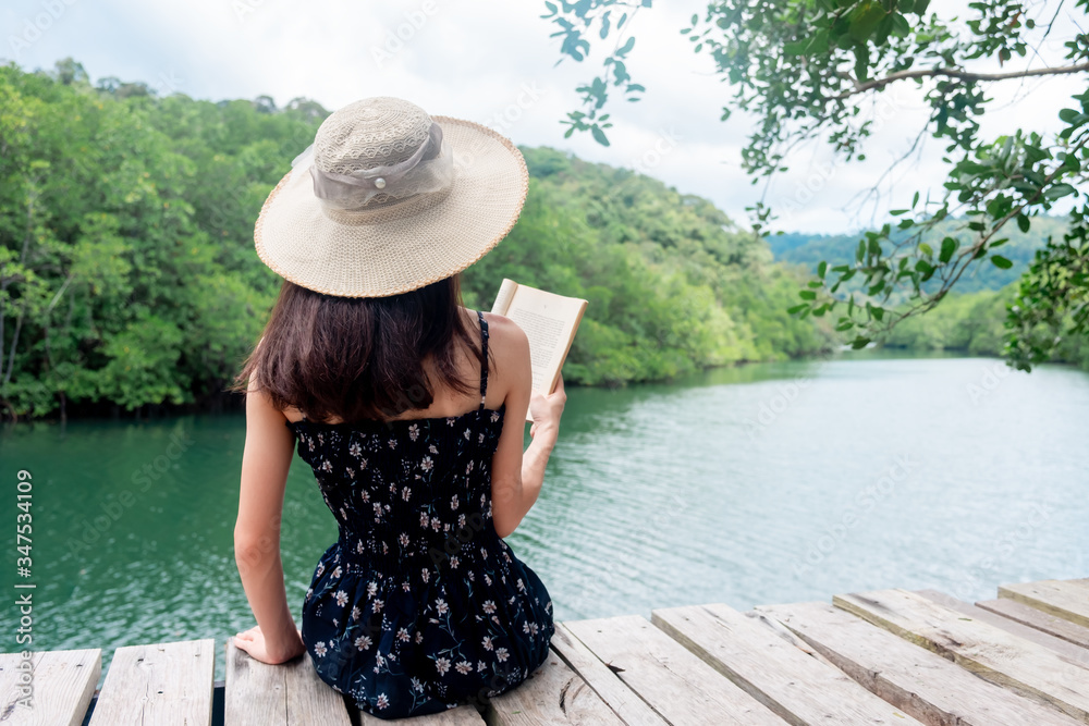 Asian women sitting reading. River view with mangrove forest. And the clear skies with beautiful clouds. Suitable for tourism, recreation and relax and intend To study knowledge