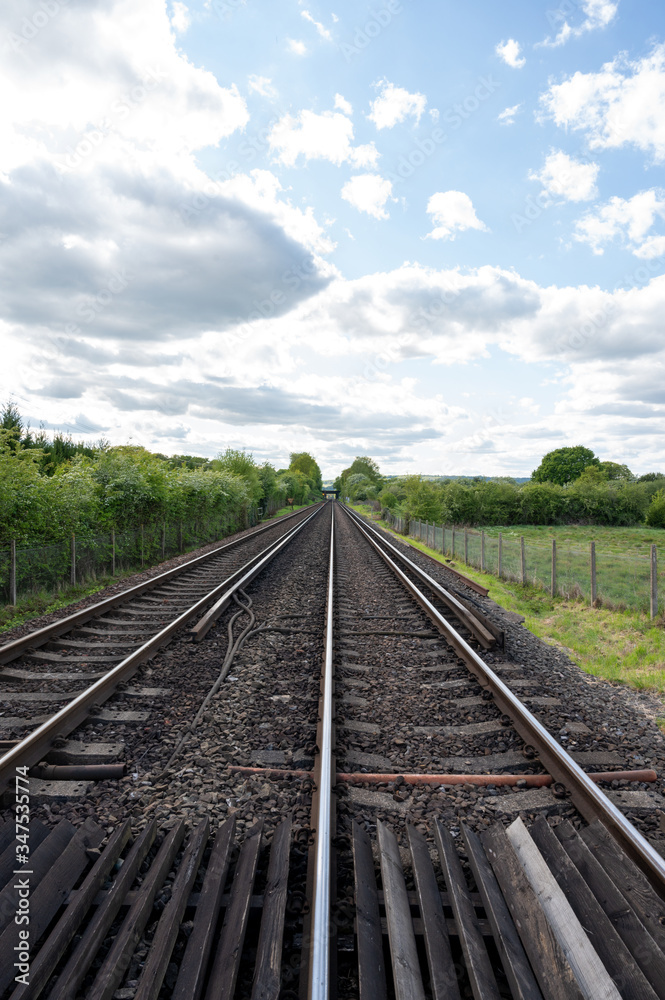 Quiet double track train line running in a straight line in the countryside.