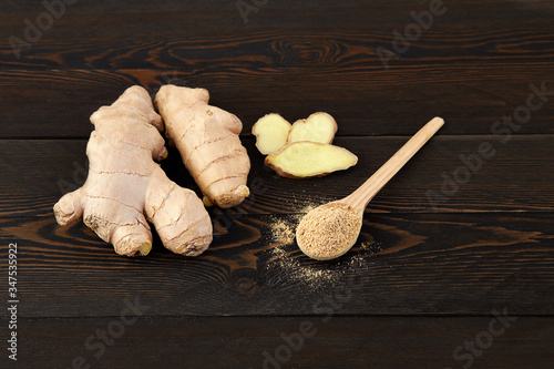 Ginger root on a dark rustic background and ground ginger in a wooden spoon photo