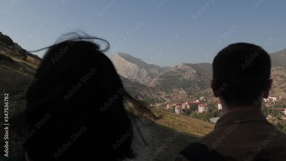 Two young people walk in the fresh air. Against the backdrop of an ancient city and huge mountains.