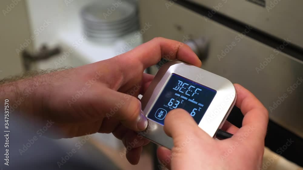 male hands set digital meat thermometer for beef to be roasting in oven male hands set digital meat thermometer for beef to be roasting in oven
