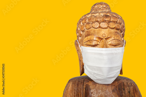 Buddha wooden statue wearing face mask photo