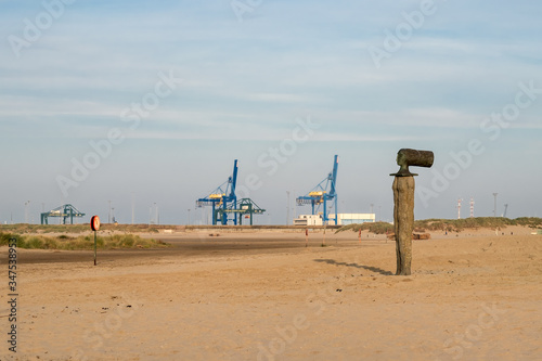 Beach of Zeebrugge with harbor cranes visible in the background