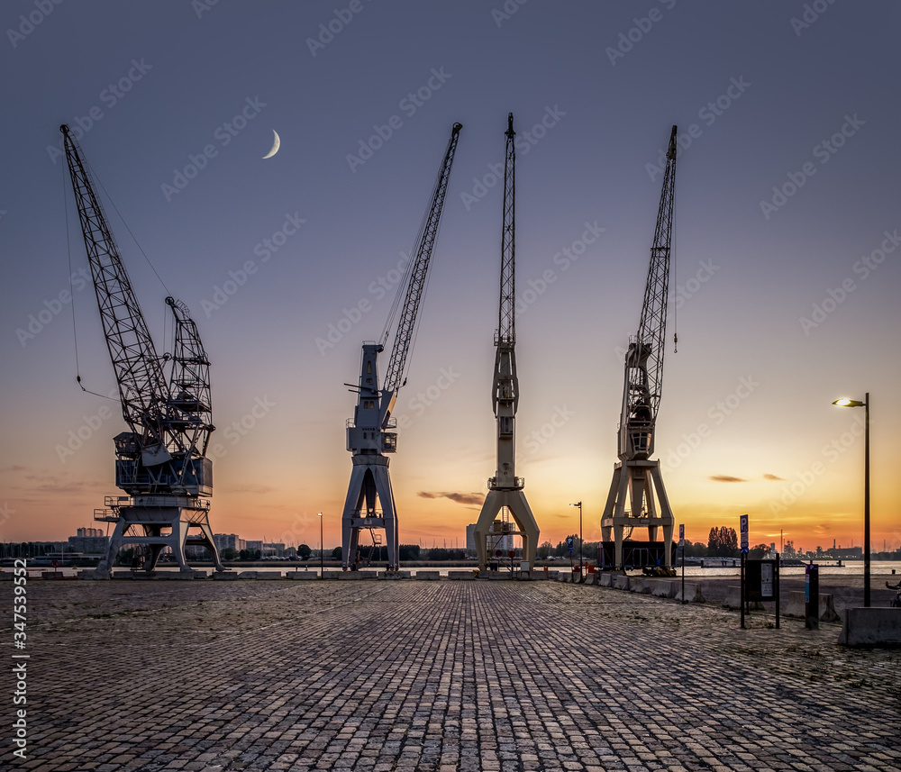 A row of 4 old harbor cranes in the city of Antwerp.