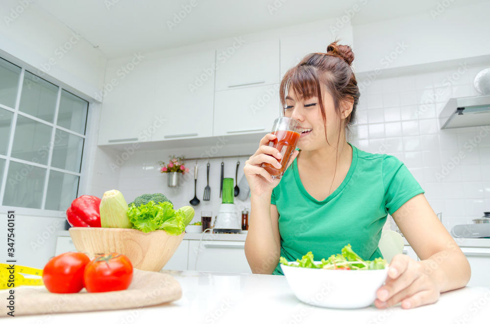 pretty asian woman slim body in green shirt dieting and drinking homemade detox juice with fresh vegetable salad sitting in at house, lifestyle, good healthy, diet food, fruit juice and drink concept