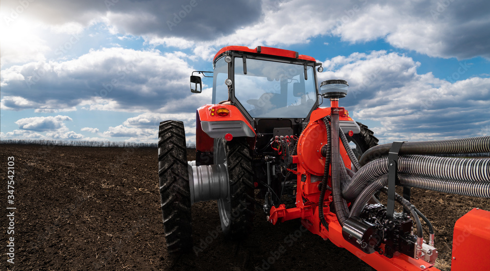 Red tractor with seeding machine on a agricultural field Red tractor with seeding machine on a agricultural field