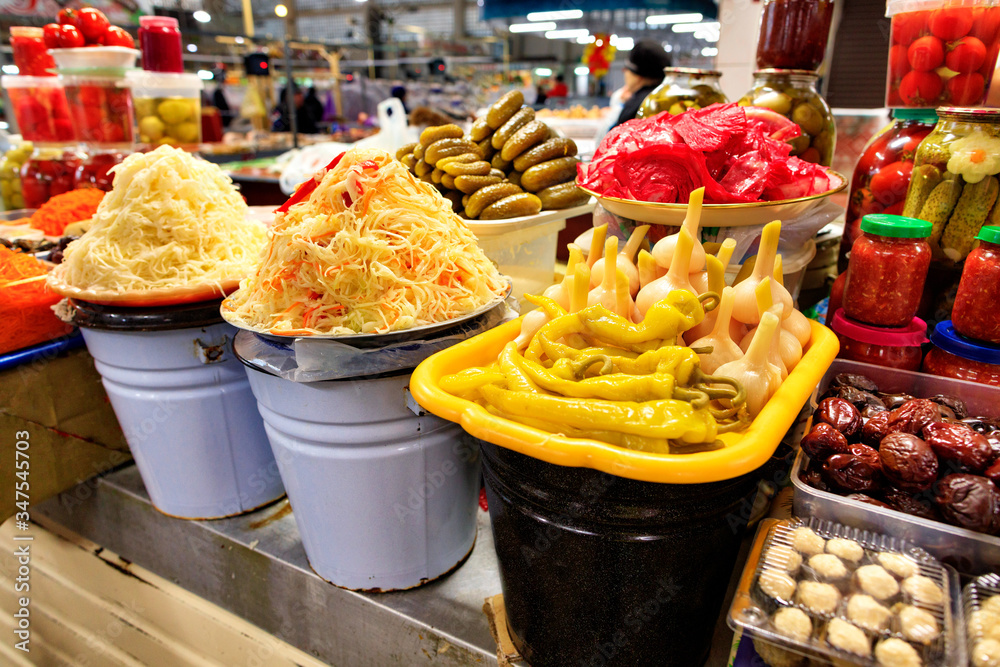 Fototapeta premium Large enamelled buckets of fermented cabbage, peppers, choppers, cucumbers, tomatoes and other vegetables are sold in the market. The concept of vegetarian food.