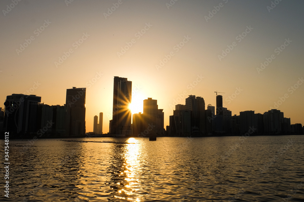 Sunset in the UAE Emirate of Sharjah-View of the river and skyscrapers. Sunset through the building.