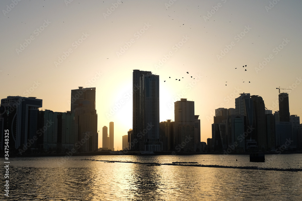 Sunset in the UAE Emirate of Sharjah-View of the river and skyscrapers. Sunset through the building.