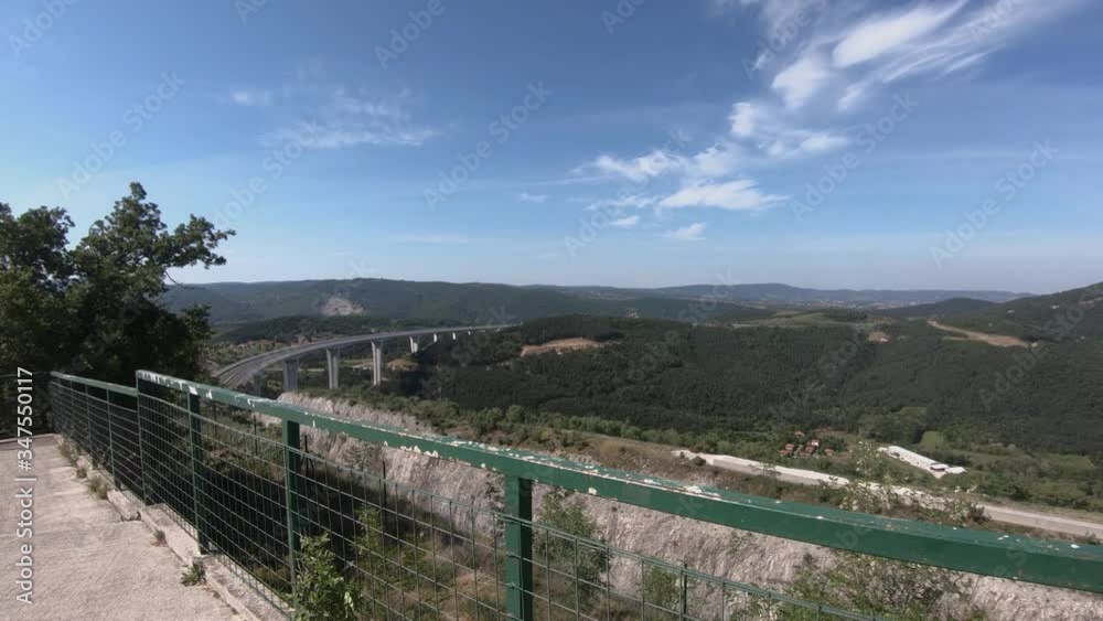 View of highway viaduct and seaside karst landscape covered with forest trees on bright sunny day. Slovenia nature in summer season. Wide shot, backward dolly moving View of highway viaduct and seaside karst landscape covered with forest trees on bright sunny day. Slovenia nature in summer season. Wide shot, backward dolly moving