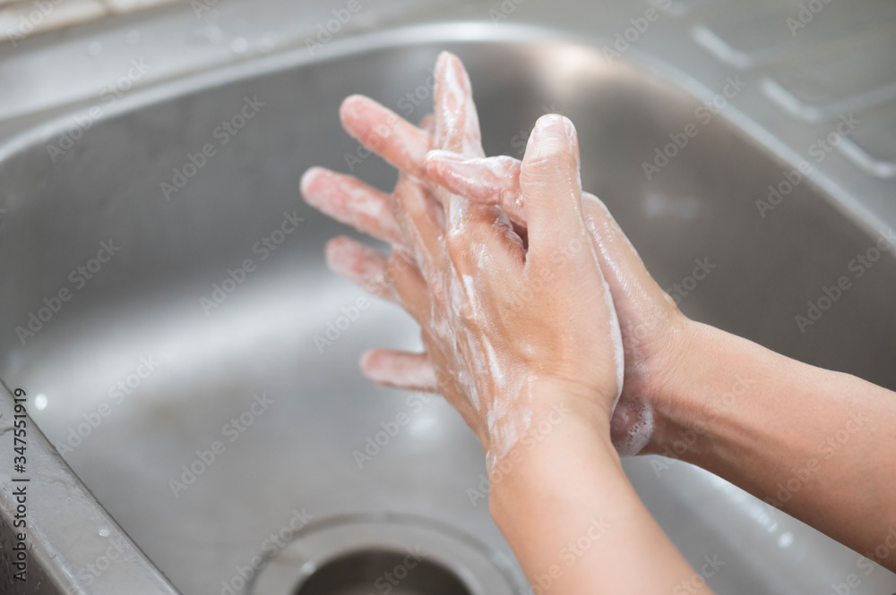 Fototapeta premium Close up woman hand washing under running water in the kitchen.Hygiene and cleaning Hands.Image hand washing step concept.