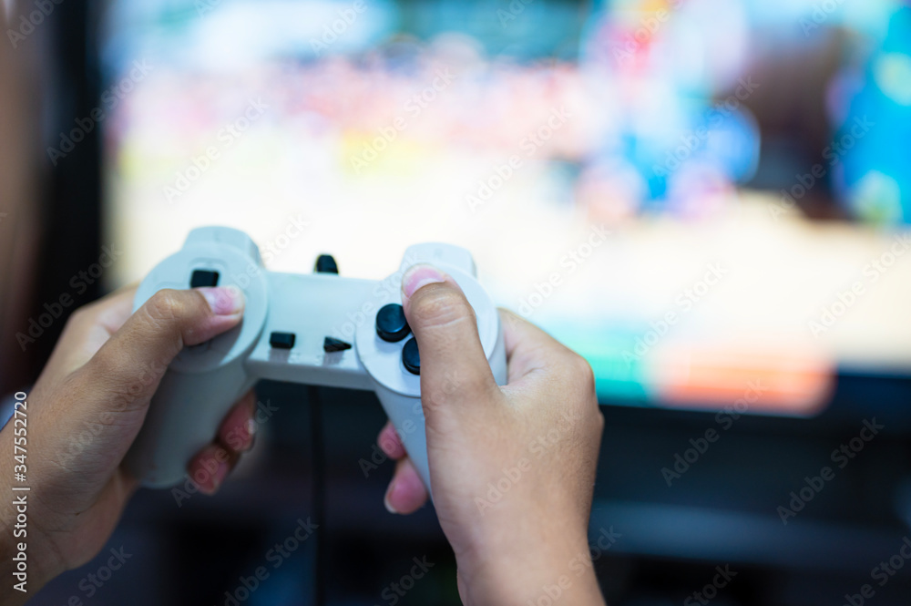 Selective focus gamer hand playing video game at home.A boy enjoy and relax with game online on TV.Stay at home concept. Selective focus gamer hand playing video game at home.A boy enjoy and relax with game online on TV.Stay at home concept.