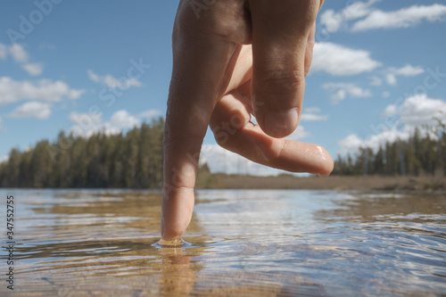 A finger touches the surface of a forest lake