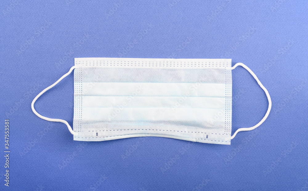 New disposable medical mask on a blue background with copy space. New disposable medical mask on a blue background with copy space.