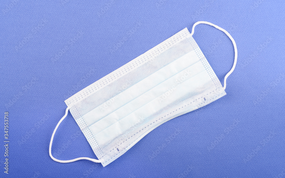 Disposable medical mask on a blue background with copy space. Disposable medical mask on a blue background with copy space.