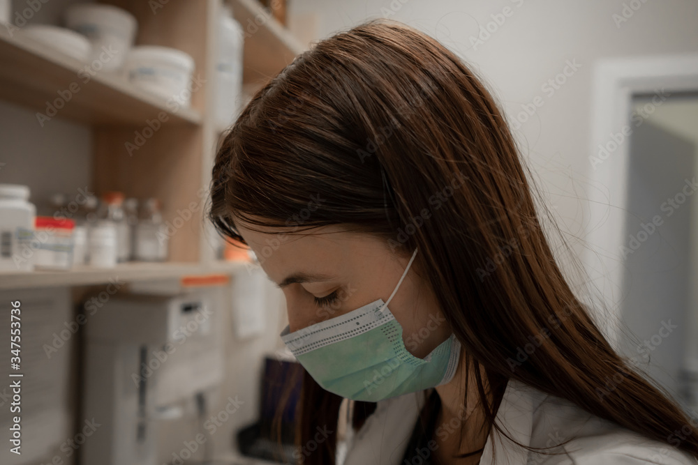 Closeup shot of tired pharmacist working during a coronavirus pandemic and wearing an anti-virus mask. Pharmacist looking for a medicines. Closeup shot of tired pharmacist working during a coronavirus pandemic and wearing an anti-virus mask. Pharmacist looking for a medicines.