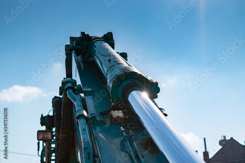 Technology, engineering and construction industry machine concept: Big excavator hydraulic cylinder on blue sky background.