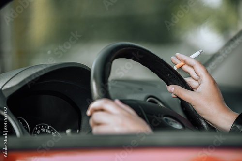 Close up of woman hand smoking cigarette inside the car while driving a vehicle