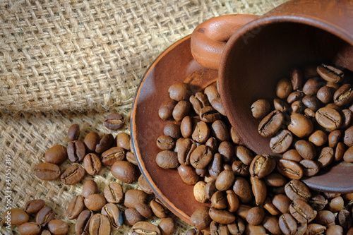 Coffee cup and roasted coffee beans on burlap. Coffee background close-up. © Andrii
