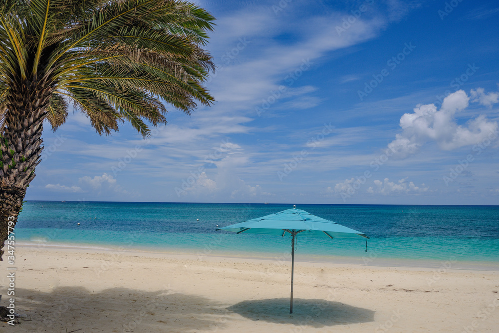 Horizontal image of an empty Cayman Island Beach with an open blue beach umbrella