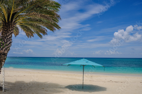 Horizontal image of an empty Cayman Island Beach with an open blue beach umbrella