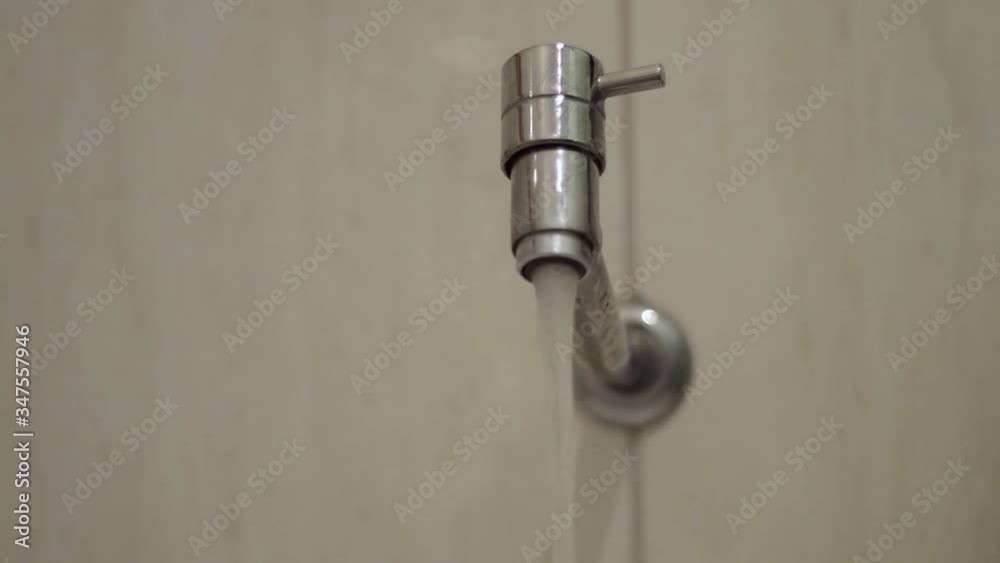 person turning on the bathroom tap, letting the water drain and then closing person turning on the bathroom tap, letting the water drain and then closing