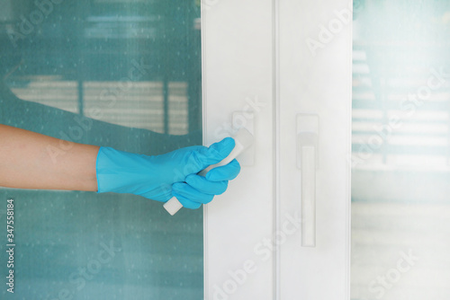 Hand wearing blue glove holding white door handle protecting allergic reaction or infectious diseases coronavirus/covid-19.