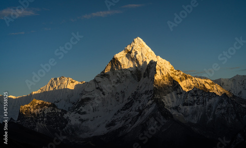 Colourful Amadablam mountain peak, known as the mother of mountains, glowing in warm sunlight during sunset. Amadablam (6812 metres/22349 ft) is an iconic and most beautiful mountain in the world.