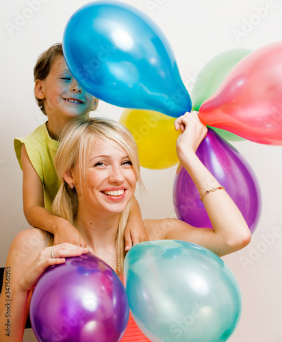 pretty real family with color balloons on white background, blond woman with little boy at birthday party bright smiling mother