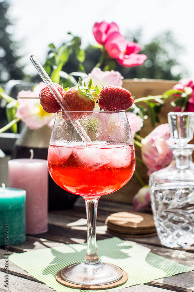 Strawberry Cocktail on a wooden table in the sun with flowers and candles Strawberry Cocktail on a wooden table in the sun with flowers and candles