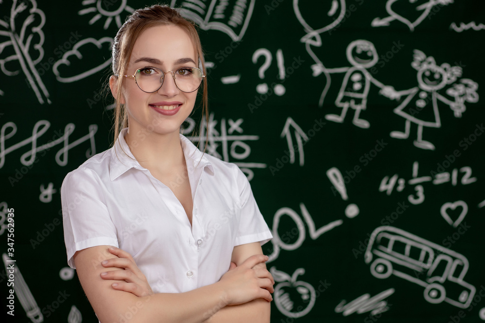 Young teacher is standing near blackboard in classroom Young teacher is standing near blackboard in classroom