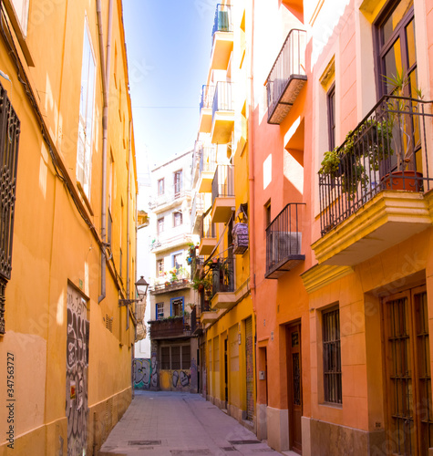 Calle estrecha con las fachadas naranjas muy iluminadas en Valencia, España