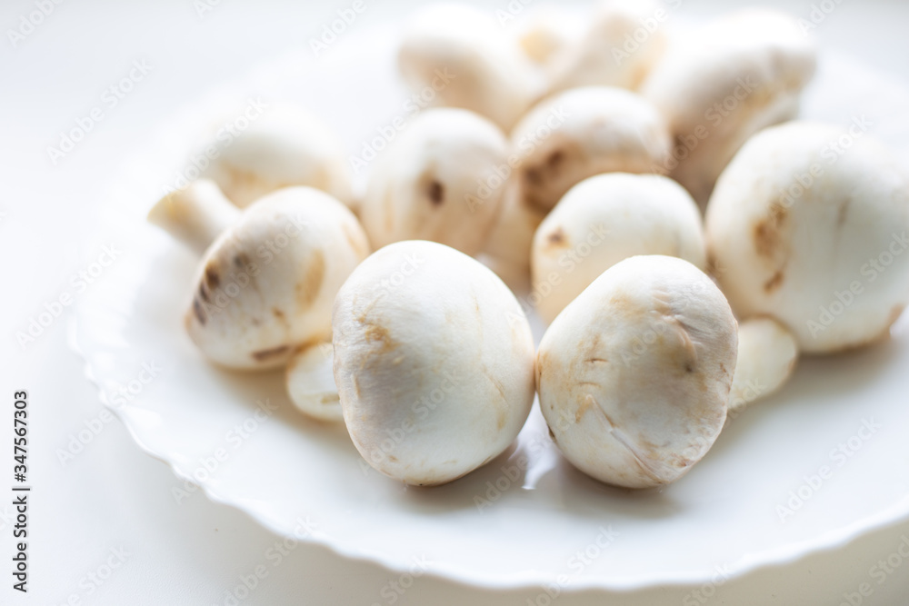 champignon mushrooms lie on a white plate, blurred background