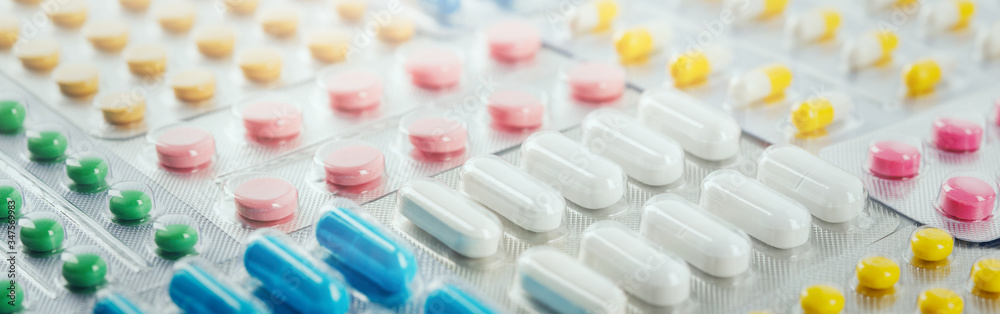 pile of medical pills  in red, blue and yellow colors in  silver plastic packaging