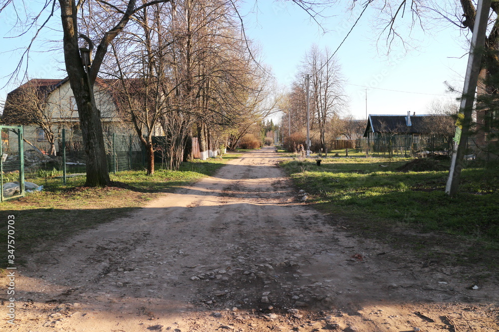 Dirt road in spring sunny evening in the village