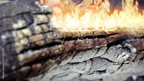 Cinemagraph of burning fire on the burnt log. Close up, loop with selective focus.